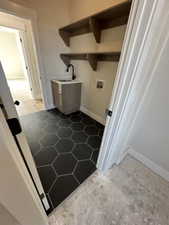 Washroom featuring a sink, laundry area, hookup for a washing machine, baseboards, and dark tile patterned flooring