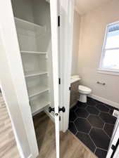 Bathroom with baseboards, wood finished floors, toilet, and vanity