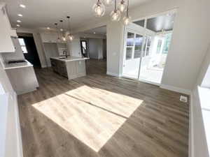 Kitchen with dark wood-type flooring, an inviting chandelier, open floor plan, and baseboards