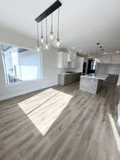 Kitchen with open floor plan, white cabinetry, light wood finished floors, and baseboards