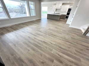 Unfurnished living room featuring baseboards and wood finished floors