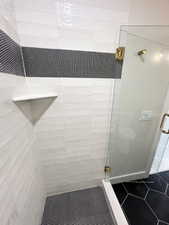 Full bath with tile patterned floors and a shower stall