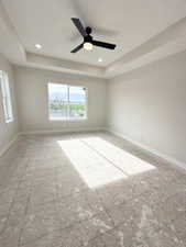 Unfurnished room with a ceiling fan, baseboards, and a tray ceiling