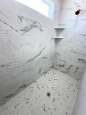 Full bath with a marble finish shower