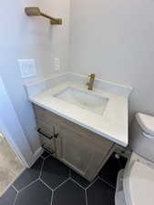 Half bath with tile patterned floors, vanity, and toilet