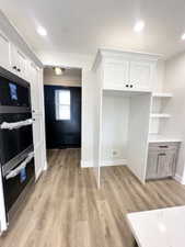 Interior space featuring light wood-type flooring, open shelves, white cabinets, and baseboards