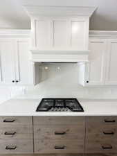 Kitchen featuring white cabinets, light stone countertops, and stainless steel gas stovetop
