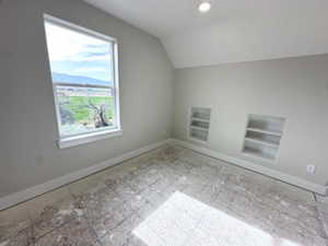 Bonus room featuring built in shelves, vaulted ceiling, and baseboards