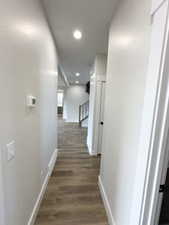 Hallway featuring baseboards, recessed lighting, and dark wood-style flooring