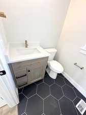 Bathroom featuring vanity, toilet, visible vents, baseboards, and tile patterned flooring