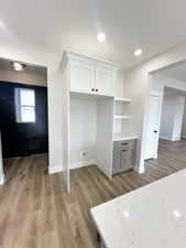 Interior space with wood finished floors, white cabinetry, open shelves, and baseboards