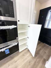 Interior details with open shelves, white cabinetry, appliances with stainless steel finishes, and light wood-style floors