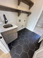Laundry area featuring hookup for a washing machine, dark tile patterned flooring, laundry area, electric dryer hookup, and a sink