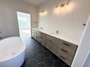 Full bathroom featuring a soaking tub, tile patterned floors, double vanity, and a sink