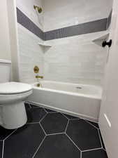 Full bathroom featuring toilet, washtub / shower combination, and tile patterned floors