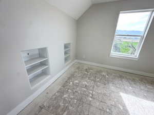 Additional living space featuring lofted ceiling, baseboards, and built in shelves