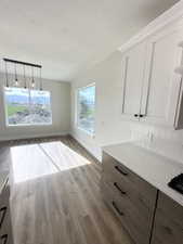 Unfurnished dining area with a textured ceiling, wood finished floors, and baseboards