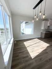 Unfurnished dining area with dark wood-style flooring and baseboards