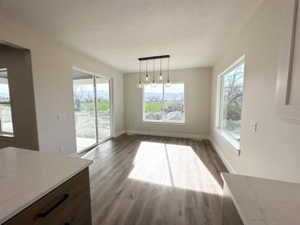Unfurnished dining area with dark wood-style floors and baseboards