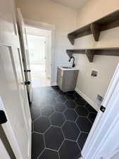 Laundry room featuring a sink, laundry area, hookup for a washing machine, baseboards, and dark tile patterned floors