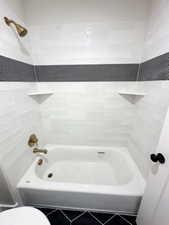 Full bathroom featuring tile patterned floors, toilet, and bathtub / shower combination