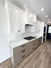 Kitchen featuring light wood-style flooring, light countertops, gas stovetop, and white cabinets