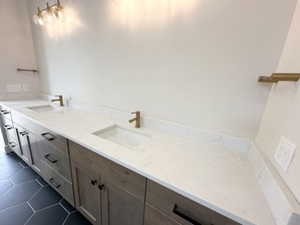 Bathroom featuring tile patterned flooring, double vanity, and a sink
