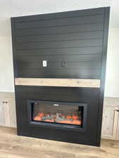 Interior details with wood finished floors, a wainscoted wall, a textured ceiling, and a glass covered fireplace