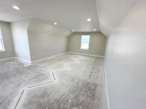 Additional living space with lofted ceiling, recessed lighting, and baseboards