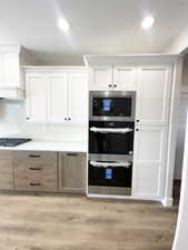 Kitchen featuring appliances with stainless steel finishes, light wood-type flooring, and white cabinets
