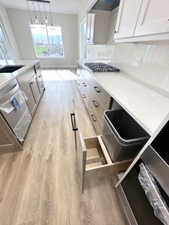 Kitchen with light wood-type flooring, light countertops, dishwasher, and stainless steel gas stovetop