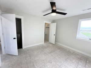 Unfurnished bedroom featuring visible vents, a walk in closet, a ceiling fan, and baseboards