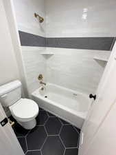 Bathroom featuring toilet, shower / bathtub combination, and tile patterned flooring