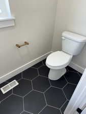 Bathroom featuring visible vents, toilet, and baseboards