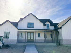 Modern farmhouse style home featuring covered porch, french doors, and board and batten siding