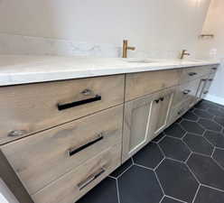 Bathroom featuring double vanity, a sink, tile patterned flooring, and baseboards