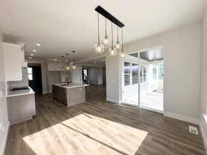 Kitchen featuring light countertops, baseboards, dark wood-style flooring, open floor plan, and an island with sink