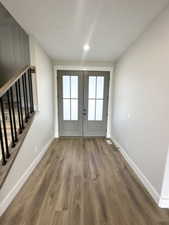 Doorway featuring baseboards, stairway, wood finished floors, and french doors