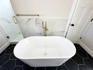 Bathroom with tile patterned floors, a shower stall, a freestanding bath, and wainscoting