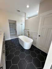 Bathroom featuring a freestanding bath, a shower stall, tile walls, vanity, and visible vents