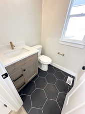Bathroom featuring toilet, tile patterned flooring, vanity, and baseboards