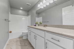 Full bathroom with toilet, baseboards, visible vents, marble finish floor, and vanity