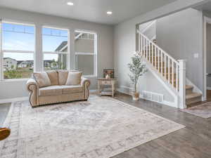 Living area featuring wood finished floors, visible vents, recessed lighting, and stairs
