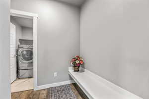 Clothes washing area with washer / dryer, wood finished floors, laundry area, and baseboards