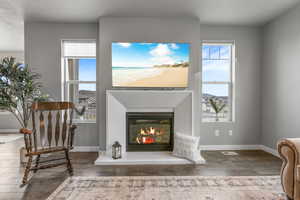 Sitting room with baseboards, a glass covered fireplace, and hardwood / wood-style floors