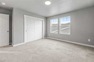 Unfurnished bedroom with baseboards, carpet flooring, and a closet