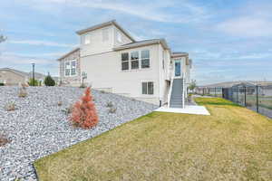 Rear view of property featuring a lawn, fence, stucco siding, a residential view, and stairs