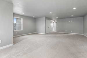 Unfurnished room featuring light colored carpet, baseboards, and recessed lighting