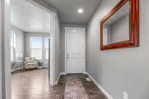 Doorway to outside with dark wood-type flooring, visible vents, baseboards, and recessed lighting