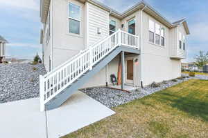 Back of house with a patio area, a lawn, and stucco siding